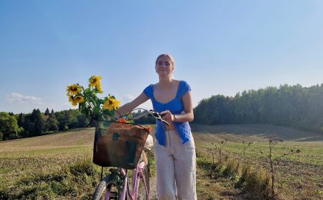 En person på ett fält gåendes med en cykel.